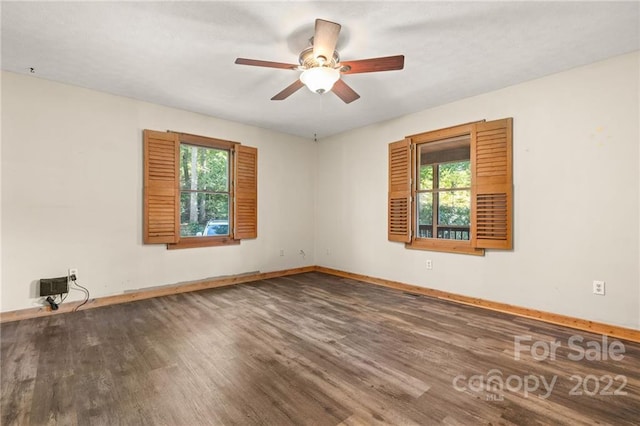 spare room with dark hardwood / wood-style floors, ceiling fan, and a wealth of natural light