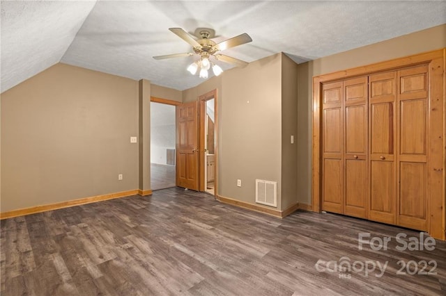 unfurnished bedroom featuring a closet, lofted ceiling, dark hardwood / wood-style floors, and ceiling fan