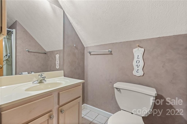 bathroom featuring tile flooring, vaulted ceiling, a textured ceiling, toilet, and vanity with extensive cabinet space