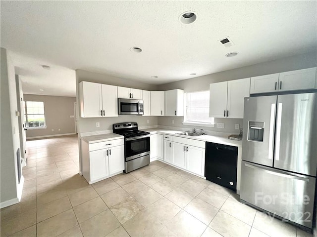 kitchen featuring sink, stainless steel appliances, white cabinetry, and a wealth of natural light