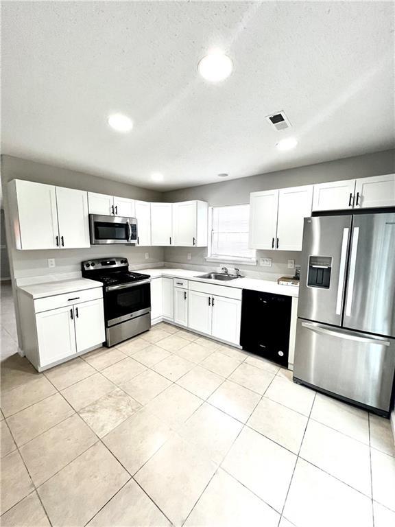 kitchen featuring light tile floors, white cabinets, sink, and stainless steel appliances