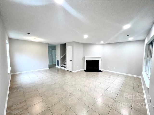 unfurnished living room with a textured ceiling and light tile floors