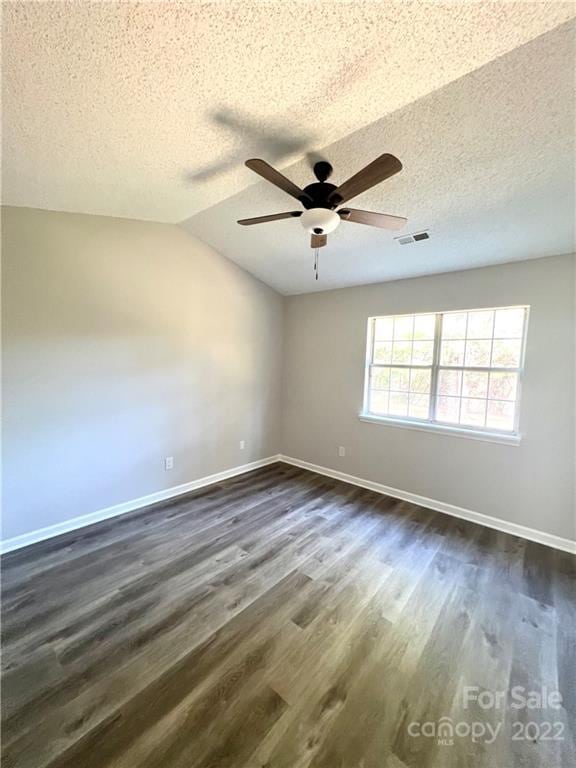 empty room with ceiling fan, lofted ceiling, a textured ceiling, and dark wood-type flooring