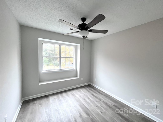 spare room with ceiling fan, a textured ceiling, and light hardwood / wood-style floors