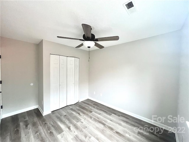 unfurnished bedroom featuring a closet, ceiling fan, and dark hardwood / wood-style flooring