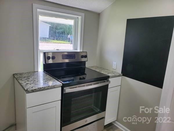 kitchen with white cabinets, light stone countertops, and stainless steel range with electric cooktop