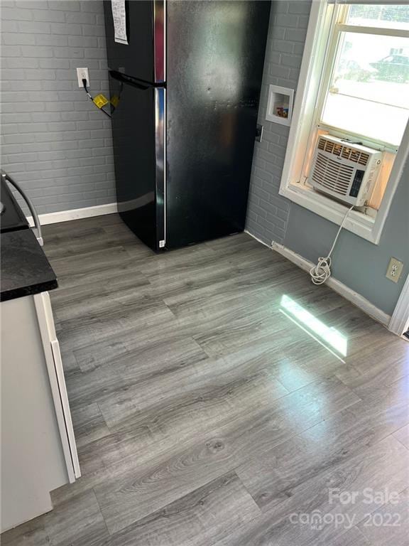 kitchen with brick wall, hardwood / wood-style floors, black refrigerator, and range