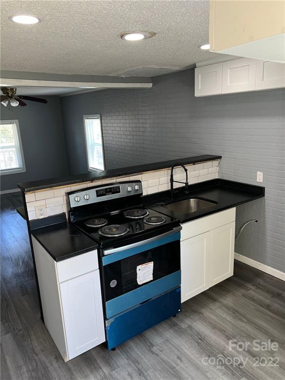 kitchen with range with electric stovetop, white cabinetry, dark hardwood / wood-style floors, ceiling fan, and sink