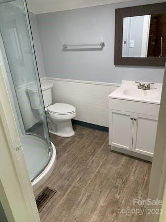 bathroom with toilet, vanity, an enclosed shower, and wood-type flooring