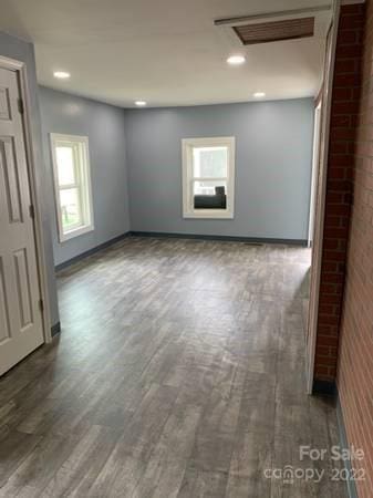 empty room with brick wall and dark wood-type flooring