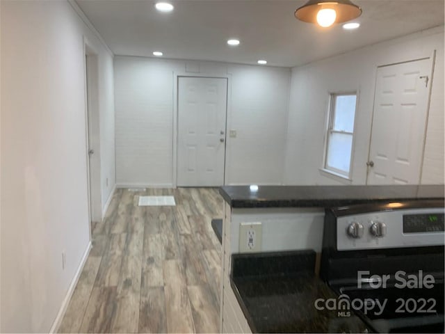 kitchen with white cabinetry, electric stove, and wood-type flooring