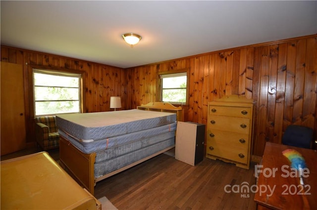 bedroom with dark hardwood / wood-style flooring and wooden walls