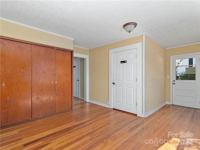 unfurnished bedroom with ornamental molding, a closet, and light wood-type flooring