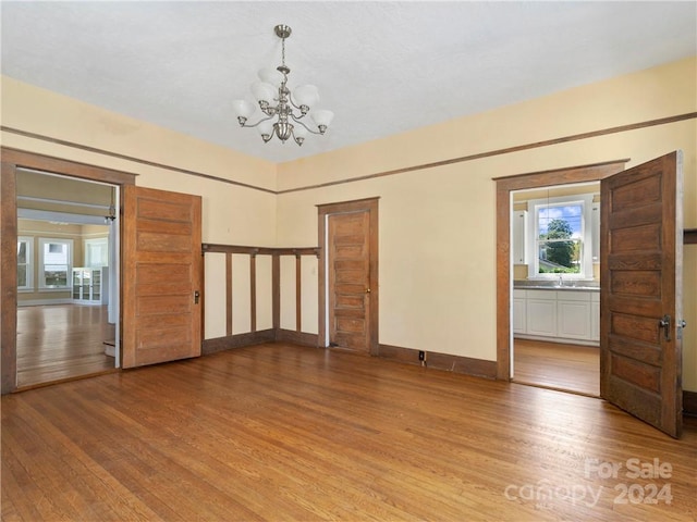 spare room featuring a notable chandelier, sink, and light wood-type flooring