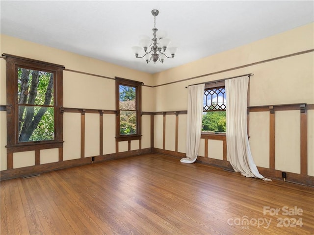 empty room with a notable chandelier and hardwood / wood-style flooring