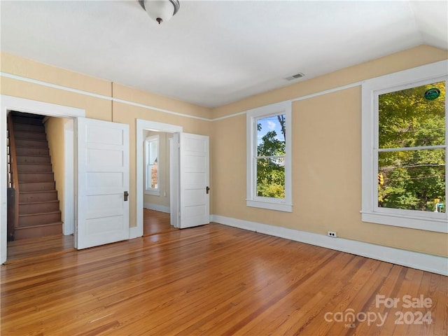 empty room with lofted ceiling and light hardwood / wood-style flooring