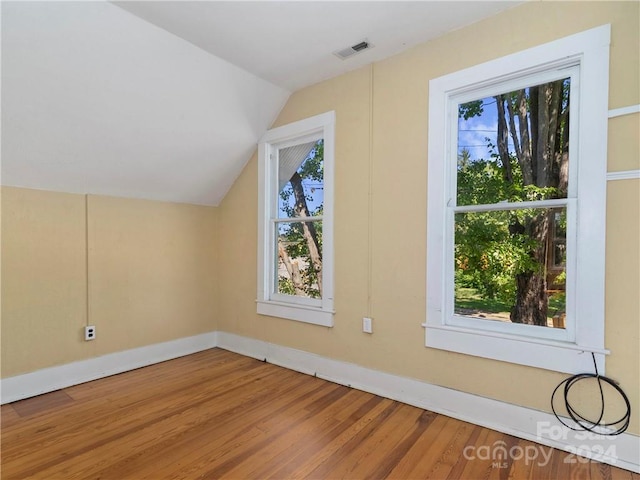 additional living space with hardwood / wood-style floors and vaulted ceiling