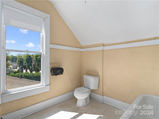 interior space with lofted ceiling, tile flooring, and toilet