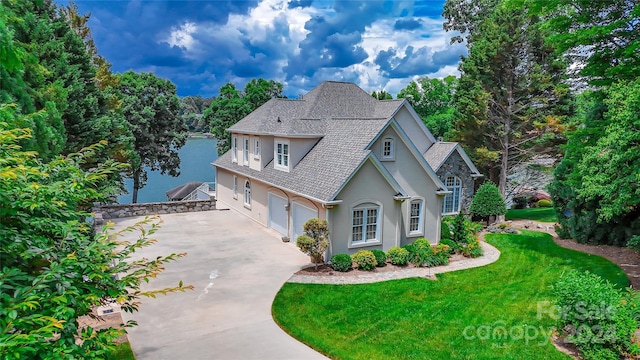 view of front of home with a front lawn, a water view, and a garage