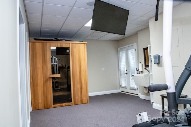 exercise area featuring a paneled ceiling and dark carpet