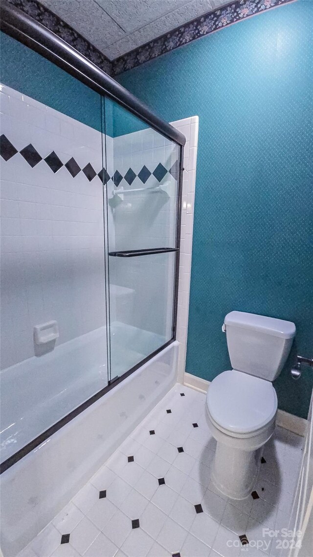 bathroom with toilet and combined bath / shower with glass door