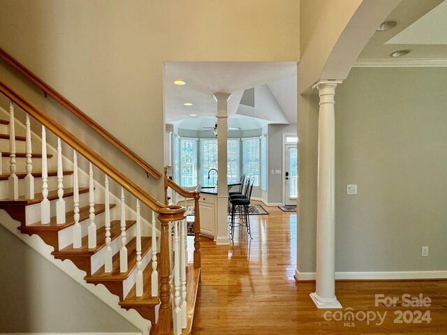 stairway with ornate columns, ceiling fan, ornamental molding, and hardwood / wood-style flooring