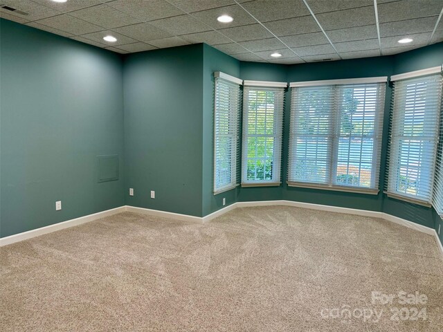 spare room featuring a paneled ceiling and carpet floors