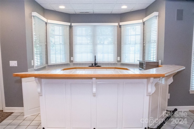 1563 Calls Lodge Ct, Morganton, NC 28655 - kitchen featuring a paneled ceiling, tile counters, light tile patterned flooring, and white cabinetry