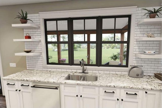 kitchen with white cabinets, a healthy amount of sunlight, light stone counters, and sink