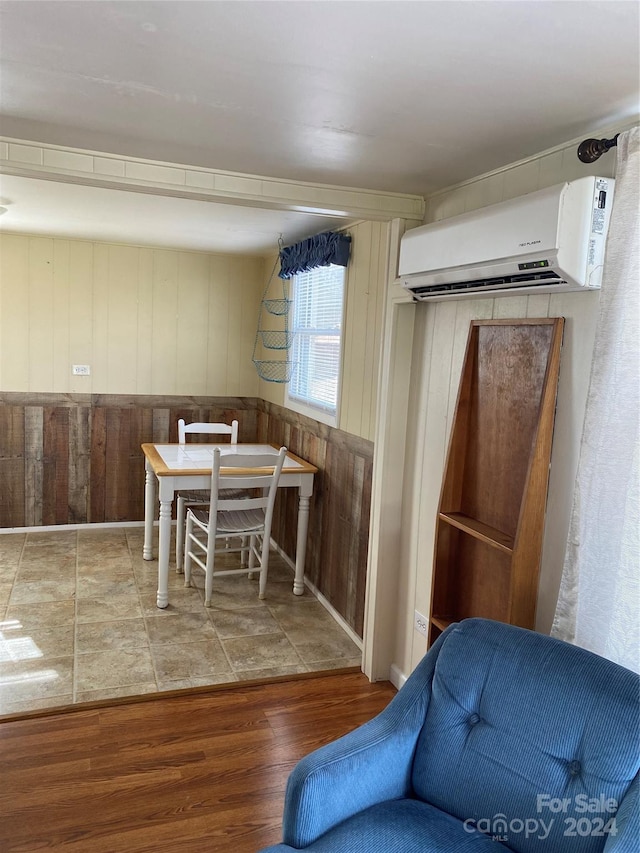 dining room featuring wooden walls, hardwood / wood-style floors, and a wall unit AC