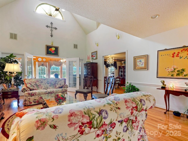 living room with a chandelier, a textured ceiling, light hardwood / wood-style flooring, and plenty of natural light