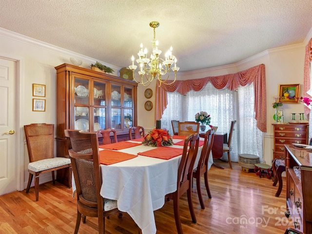 dining space featuring a textured ceiling, light wood-type flooring, crown molding, and a chandelier