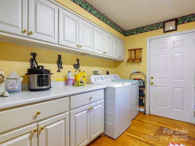 laundry room with washing machine and clothes dryer, cabinets, and light wood-type flooring