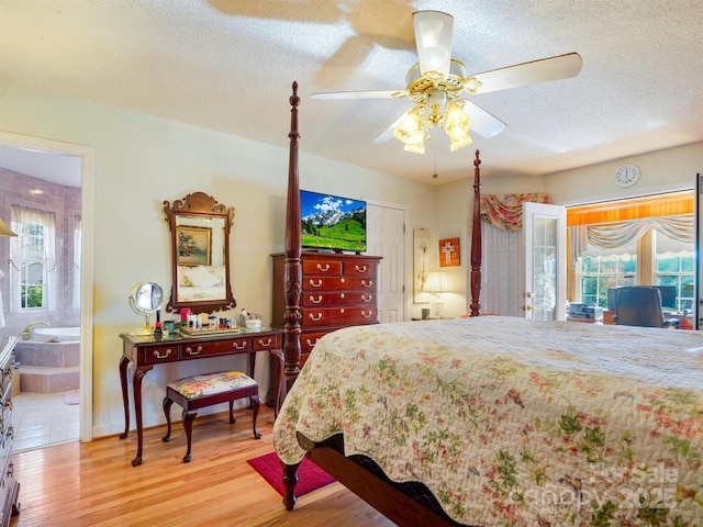 bedroom with ensuite bath, ceiling fan, light hardwood / wood-style flooring, and a textured ceiling