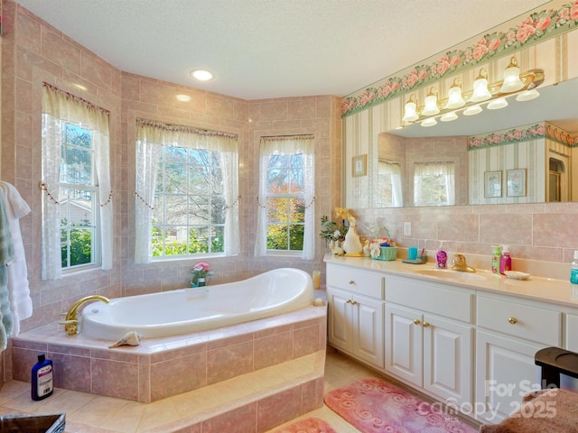 bathroom featuring tiled bath, tile patterned flooring, vanity, and a textured ceiling