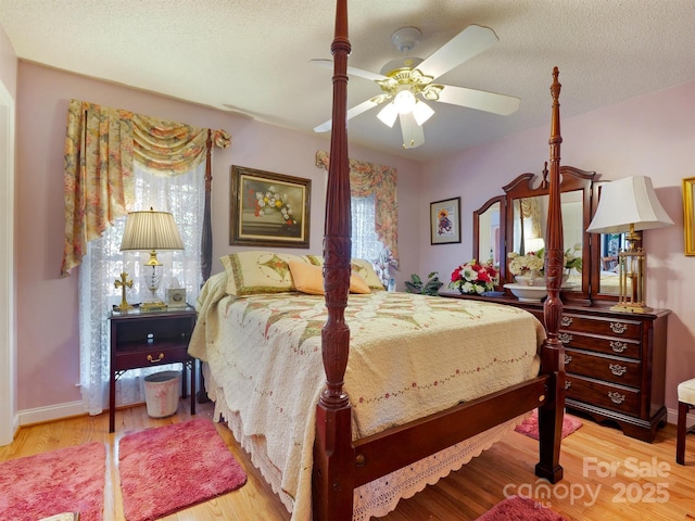 bedroom with a textured ceiling, light hardwood / wood-style floors, and ceiling fan