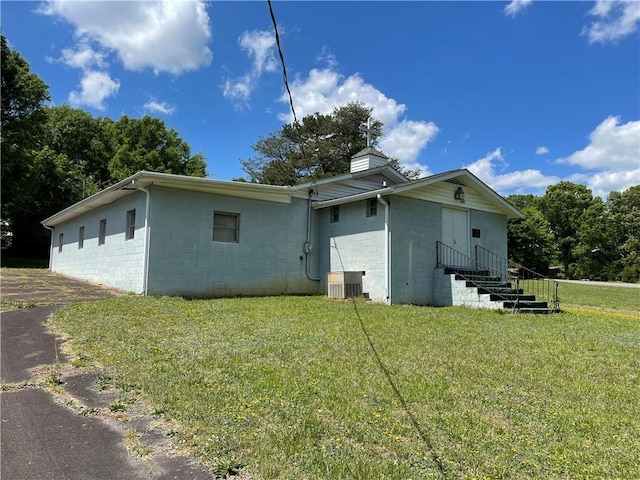 rear view of house featuring central AC and a yard