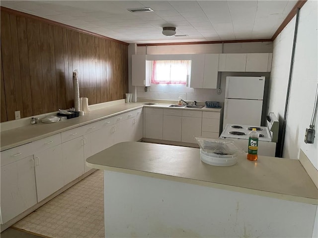 kitchen featuring wood walls, white fridge, white cabinets, light tile floors, and sink