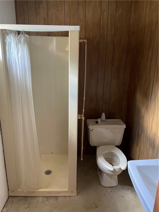 bathroom featuring toilet, wood walls, and a shower with shower curtain