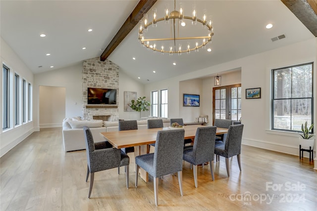 dining area featuring lofted ceiling with beams, light hardwood / wood-style floors, a notable chandelier, and a fireplace