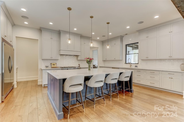 kitchen with an island with sink, stainless steel appliances, and light hardwood / wood-style flooring