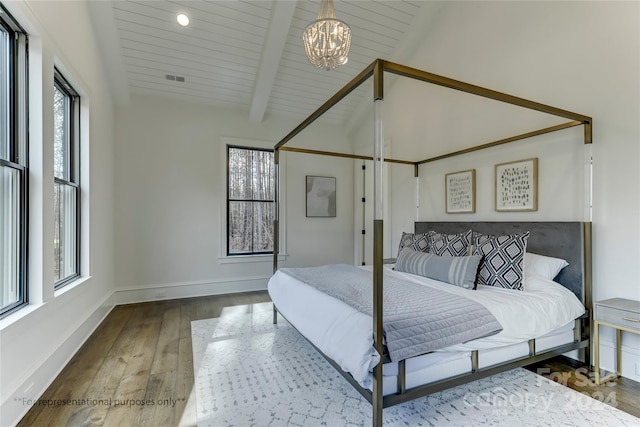 bedroom featuring dark hardwood / wood-style floors, a notable chandelier, and vaulted ceiling with beams