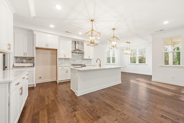 kitchen with white cabinets, dark hardwood / wood-style flooring, a kitchen island with sink, and wall chimney range hood