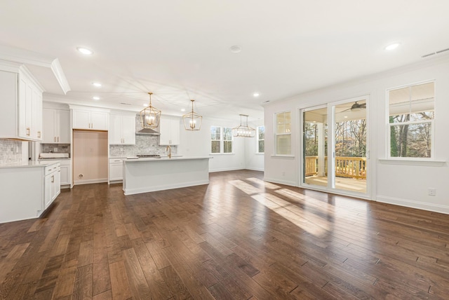 interior space with crown molding, a healthy amount of sunlight, ceiling fan with notable chandelier, and dark wood-type flooring