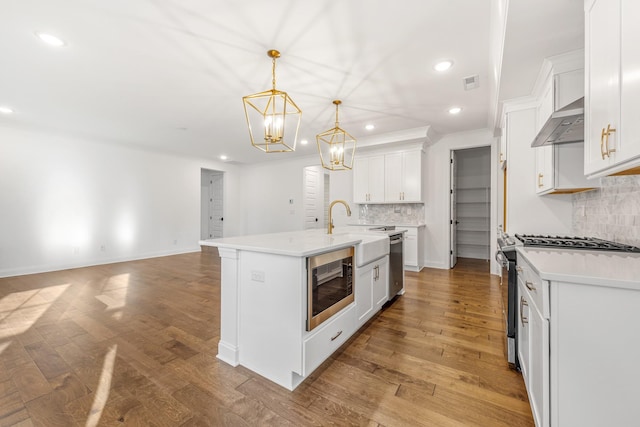 kitchen featuring backsplash, an island with sink, stainless steel appliances, and light wood-type flooring