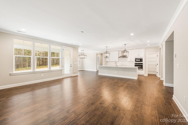 unfurnished living room featuring dark hardwood / wood-style flooring, ornamental molding, and sink