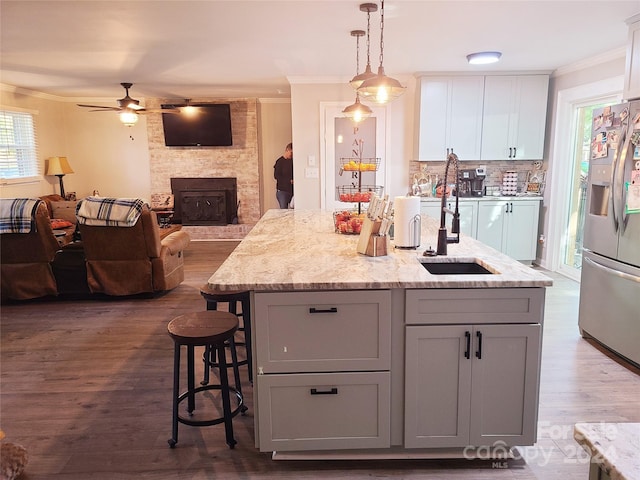 kitchen featuring ceiling fan, a large fireplace, stainless steel fridge, dark hardwood / wood-style flooring, and ornamental molding