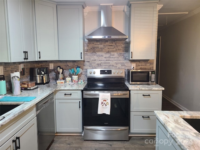 kitchen with light stone countertops, dark wood-type flooring, backsplash, wall chimney exhaust hood, and appliances with stainless steel finishes