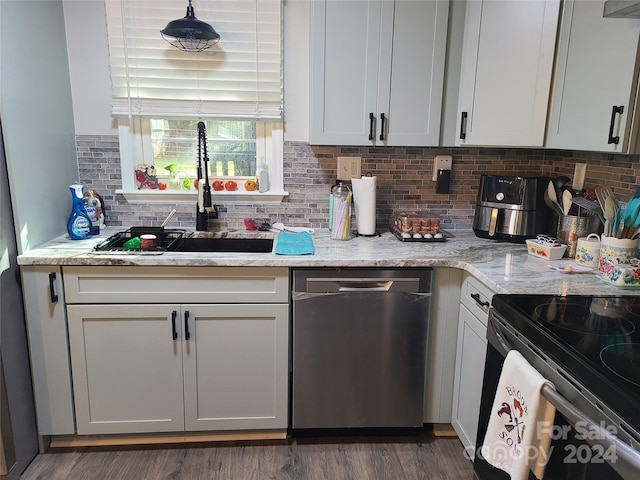 kitchen featuring dark wood-type flooring, light stone counters, backsplash, sink, and dishwasher