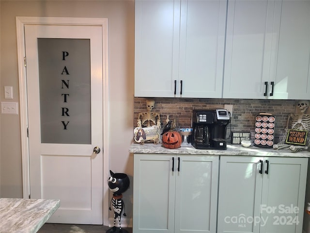 kitchen with white cabinets, light stone counters, and backsplash